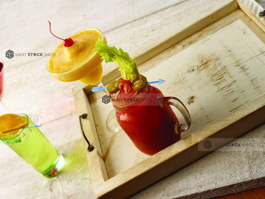 Bloody mary / caesar with tropical margarita and highball cocktail on a wooden tray