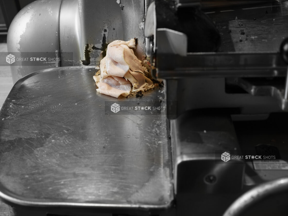 Commercial meat slicer shaving turkey breast in a restaurant