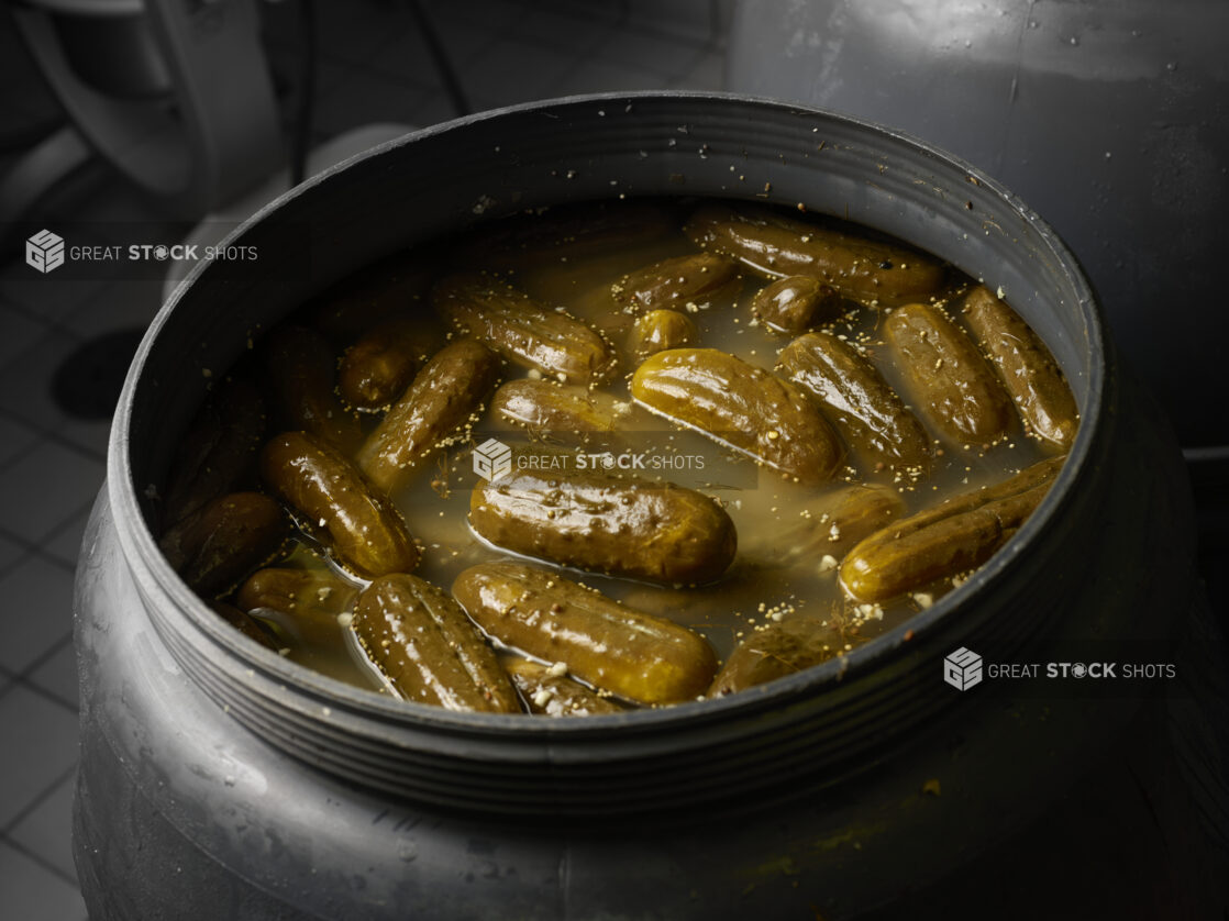 Pickles brining in a large black vat inside a restaurant