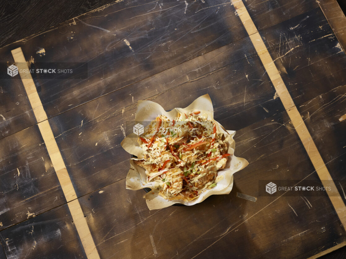 Overhead view of wonton nachos with red peppers, green onions, shredded cheese and drizzled with creamy sauce