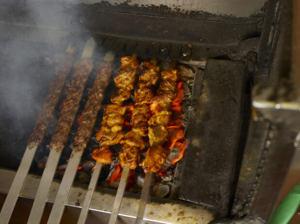Skewers of kofta and chicken kebab over an open charcoal flame
