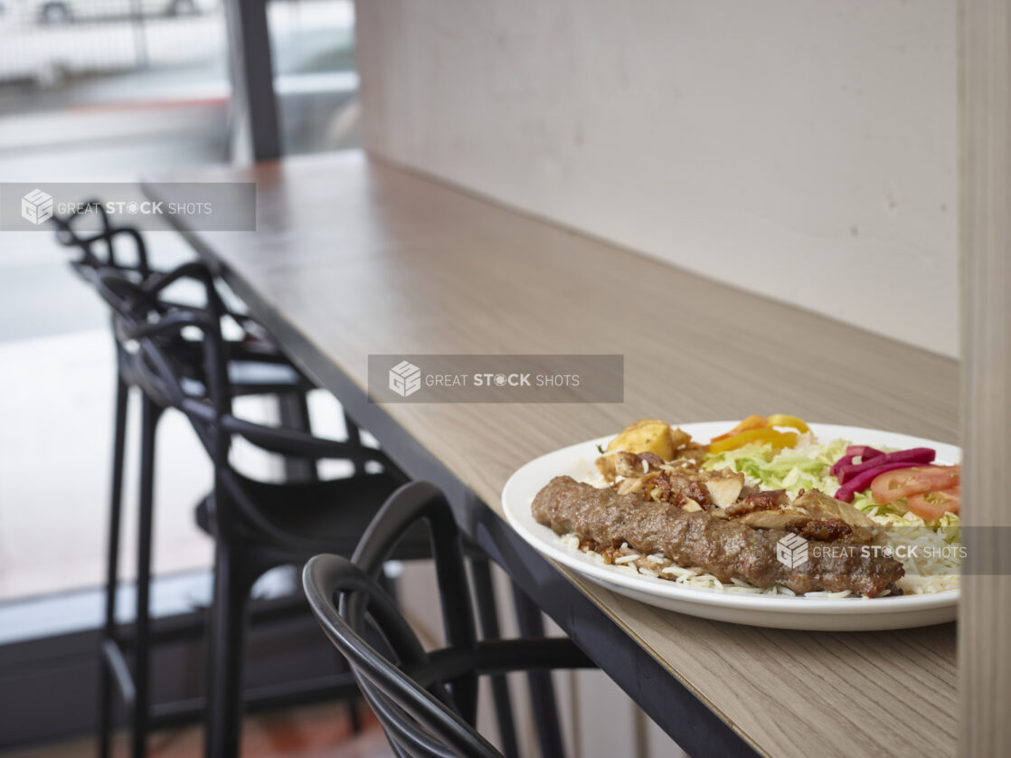 Middle eastern plate of mixed meats, rice, salad and potatoes on a plate in a restaurant