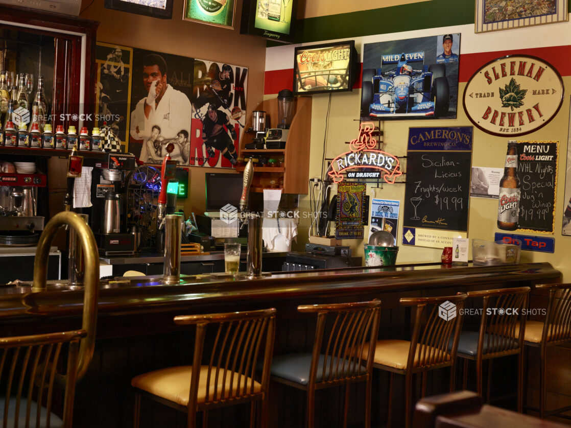 View of bar with stools inside of a dimly lit restaurant