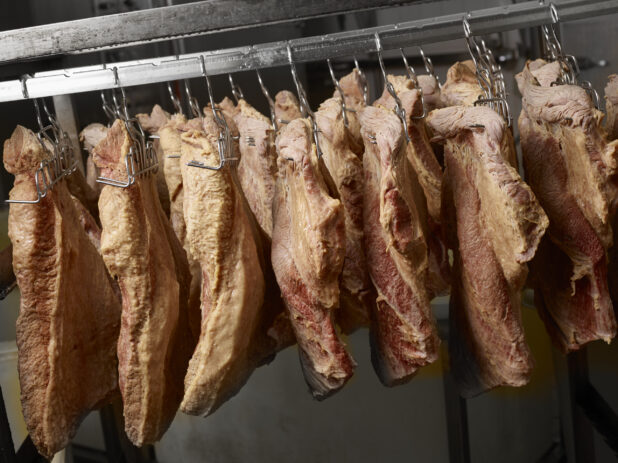 Guanciale curing on meat hooks