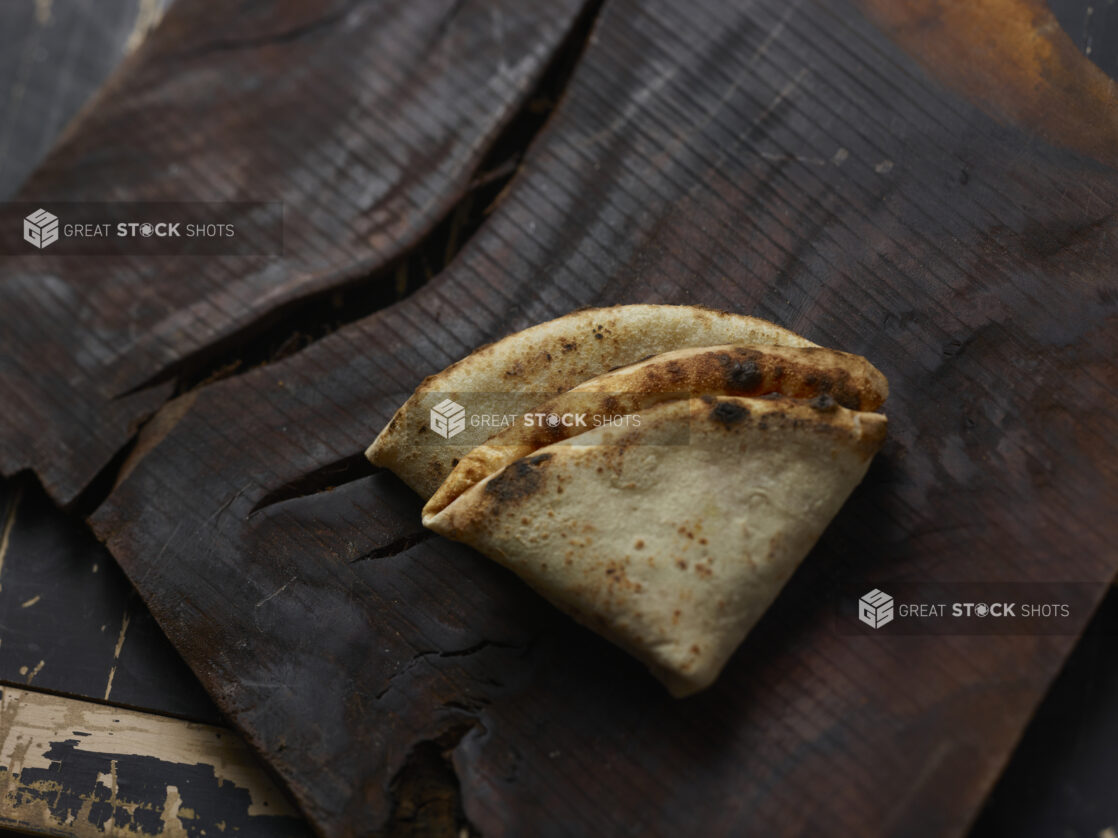 Folded wood fire pizza crust on a dark background, close-up