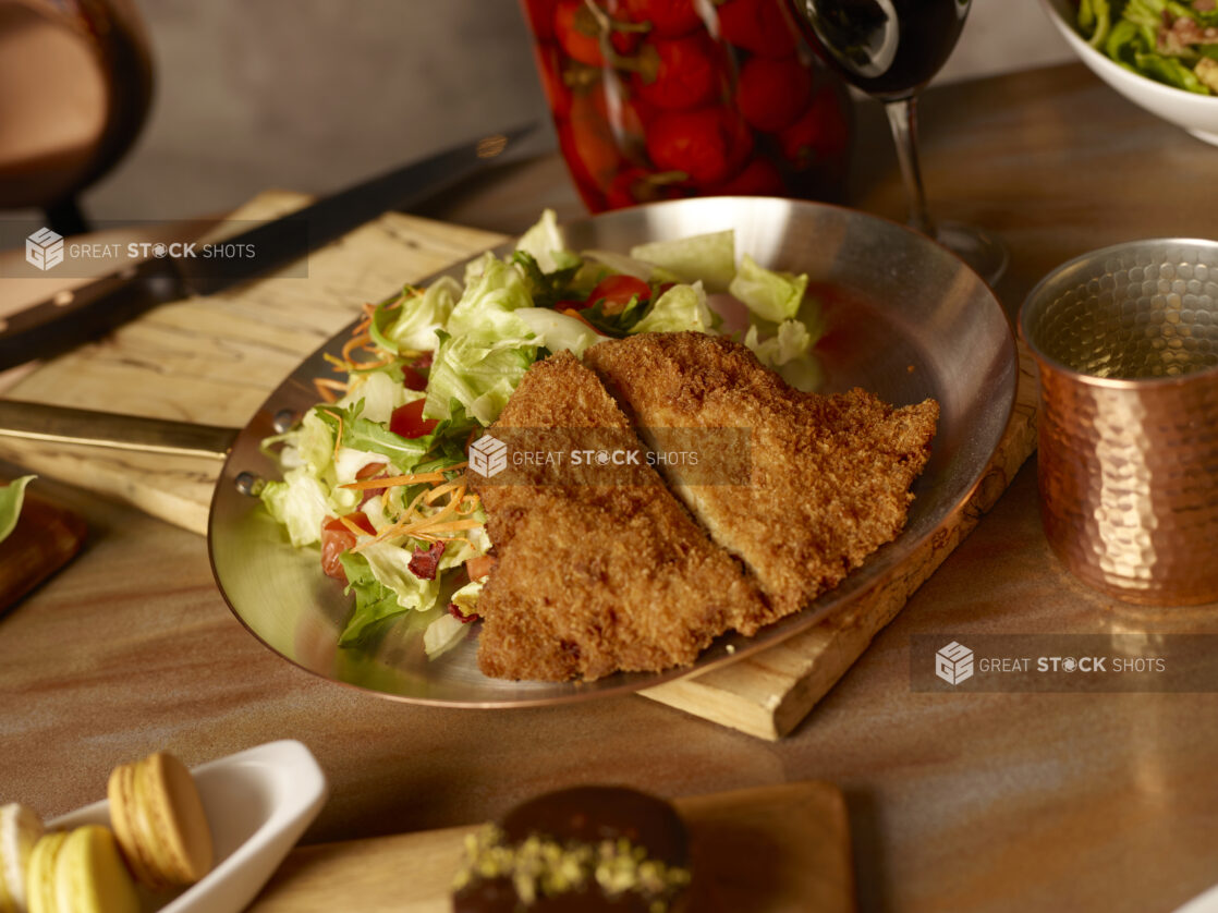 Crispy fried chicken with side garden salad on a metal frying pan