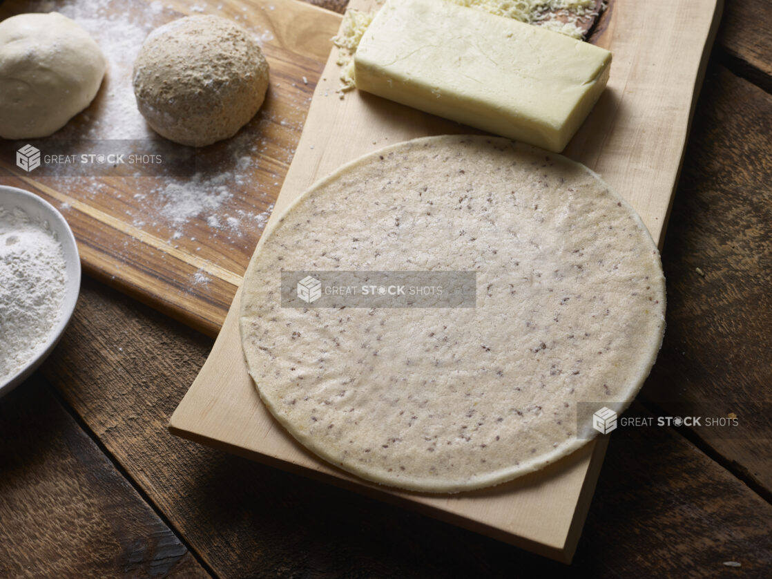 Dough balls and gluten-free pizza crust with cheese on wooden boards on a wooden background