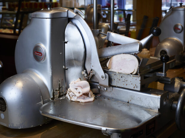 Side view of oven roasted turkey in commercial grade meat slicer