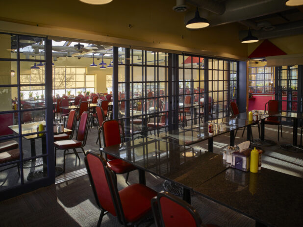 Large empty restaurant with red chairs and sectioned off rooms