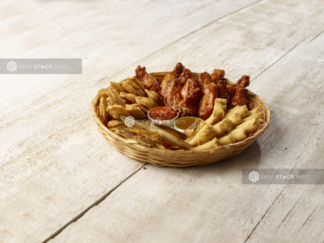 Sampler basket of appetizers with dips on a wooden background