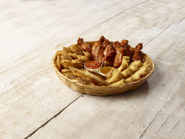 Sampler basket of appetizers with dips on a wooden background