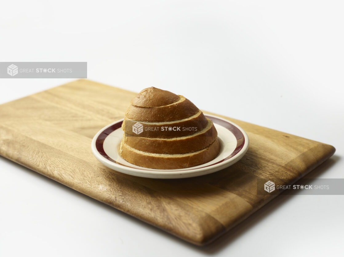 Stack of sliced rye bread on a plate on a wooden board with a white background