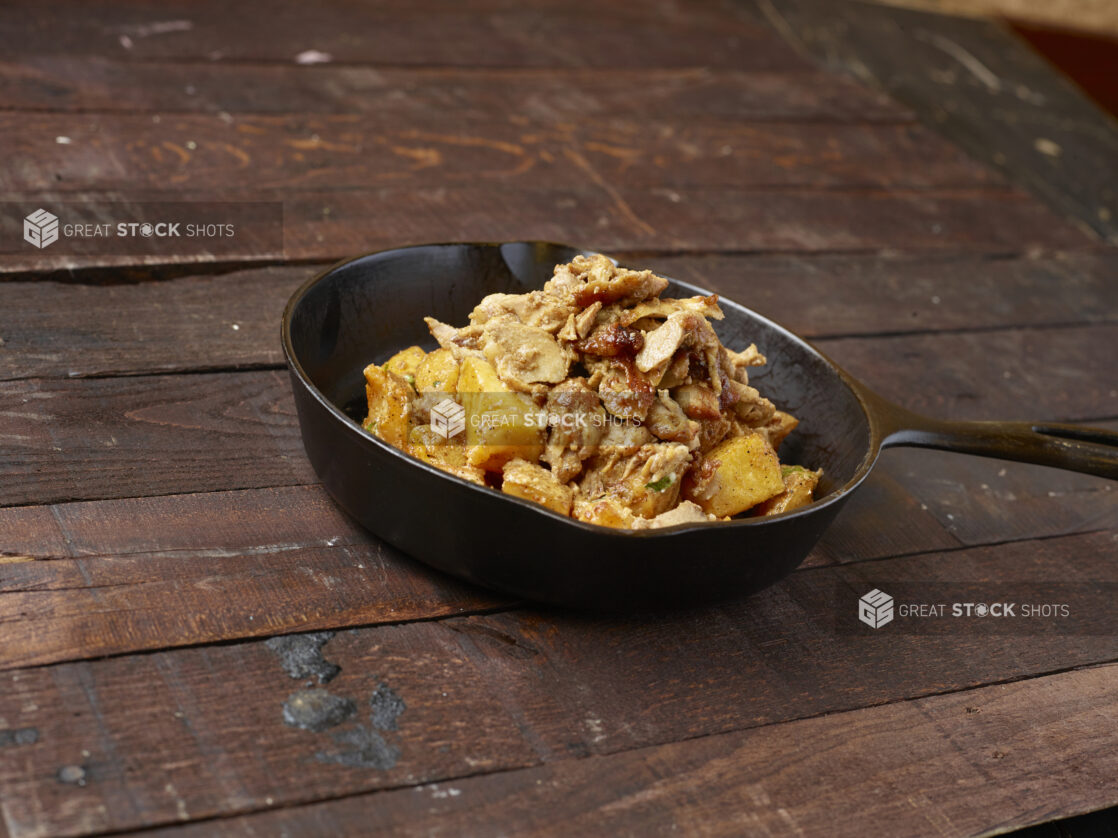 Chicken shawarma, potatoes in a black iron skillet topped with tabouli on dark wood background