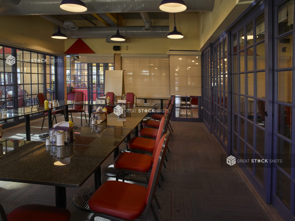 Large empty meeting space in a restaurant with red chairs and paned glass walls