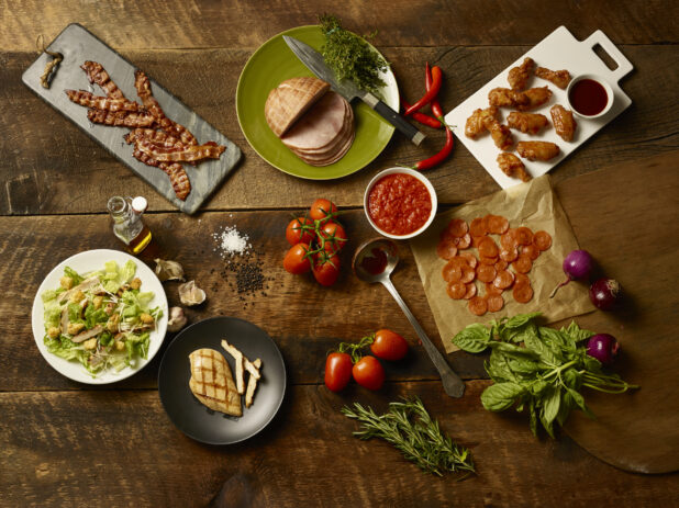 Fresh pizza ingredients and appetizers on a wooden background, overhead