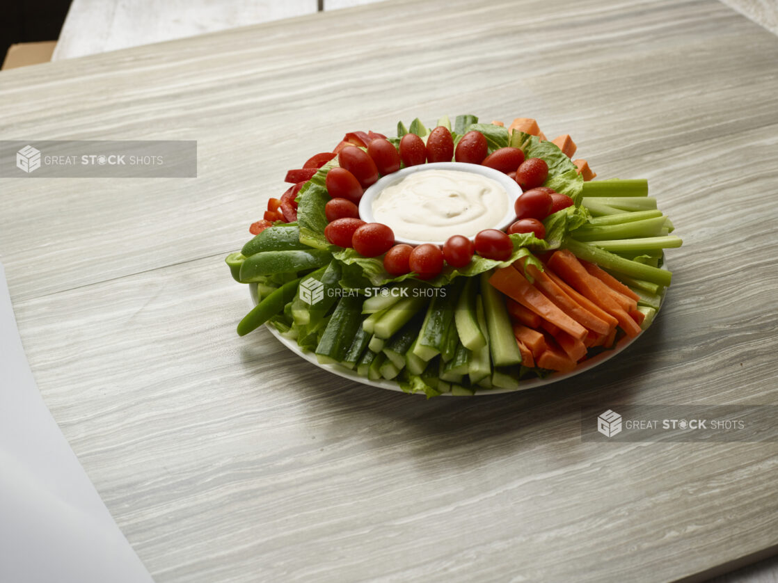 Large vegetable platter with creamy dip in the center on a wooden background