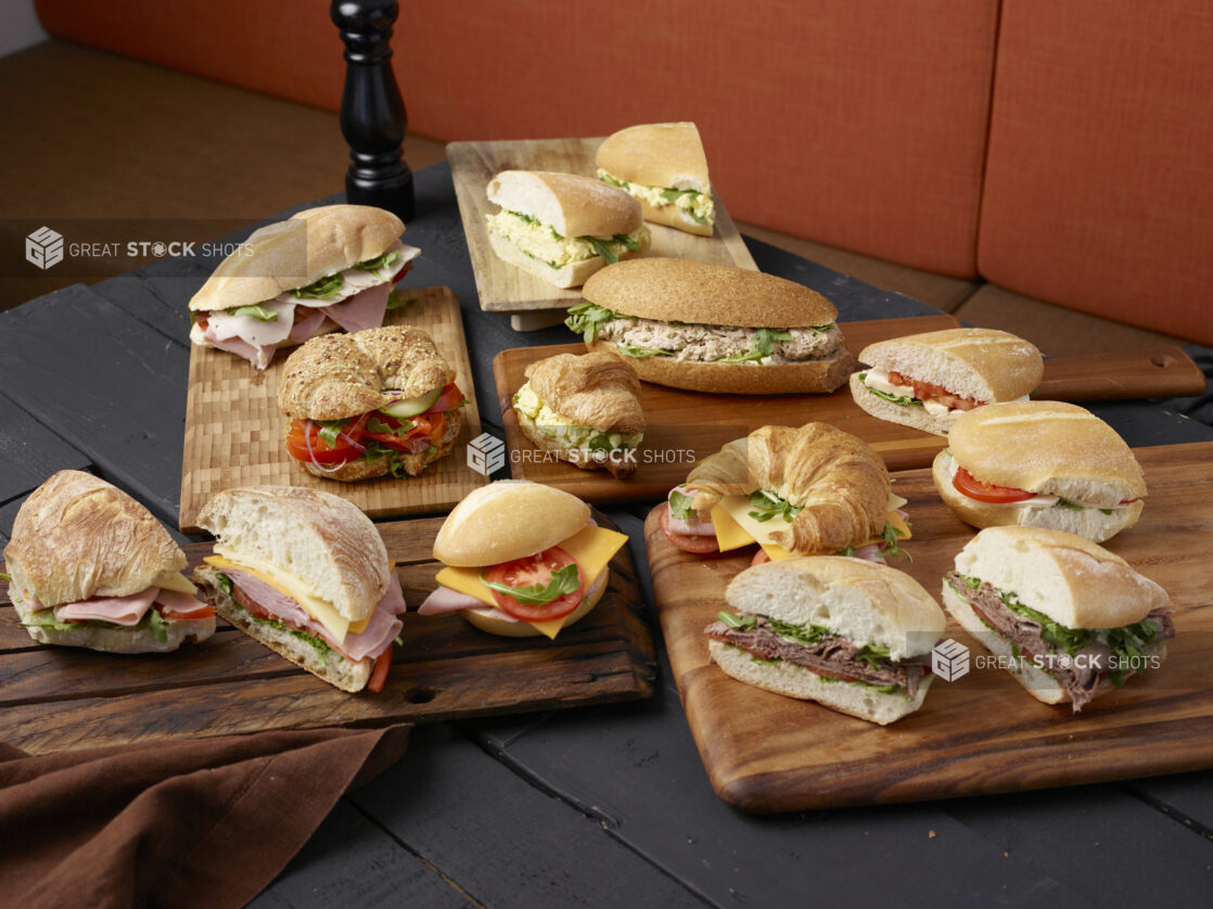 Various sandwiches on wooden boards with a dark wooden background