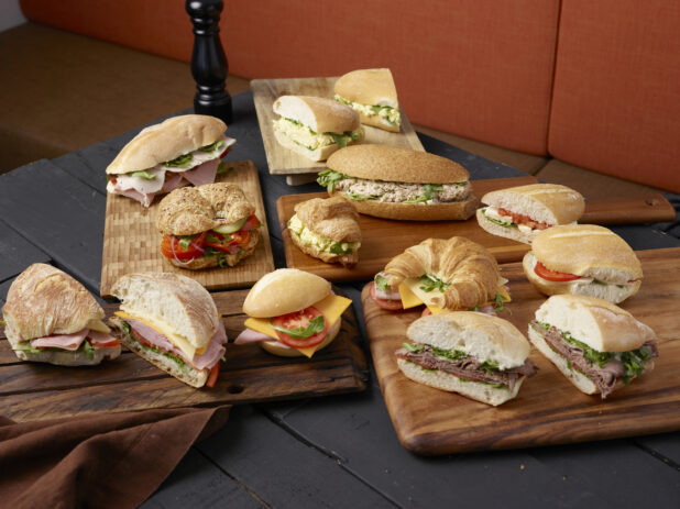 Various sandwiches on wooden boards with a dark wooden background