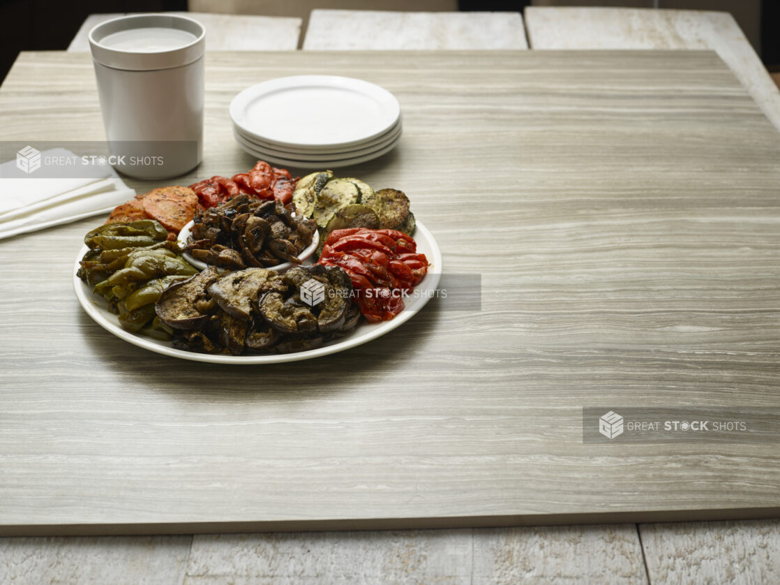 Platter of grilled vegetables on a round white plate on a wooden background