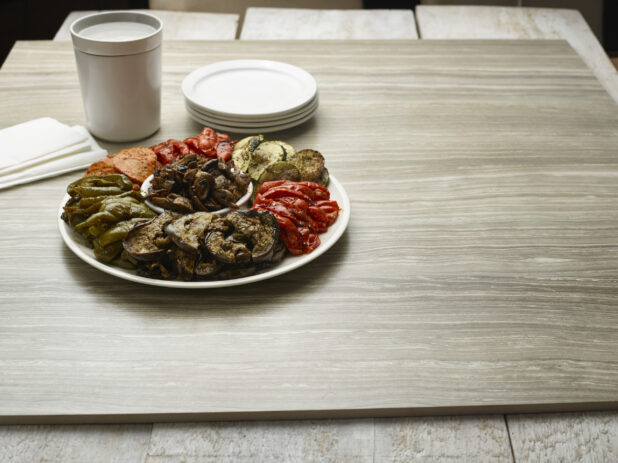 Platter of grilled vegetables on a round white plate on a wooden background