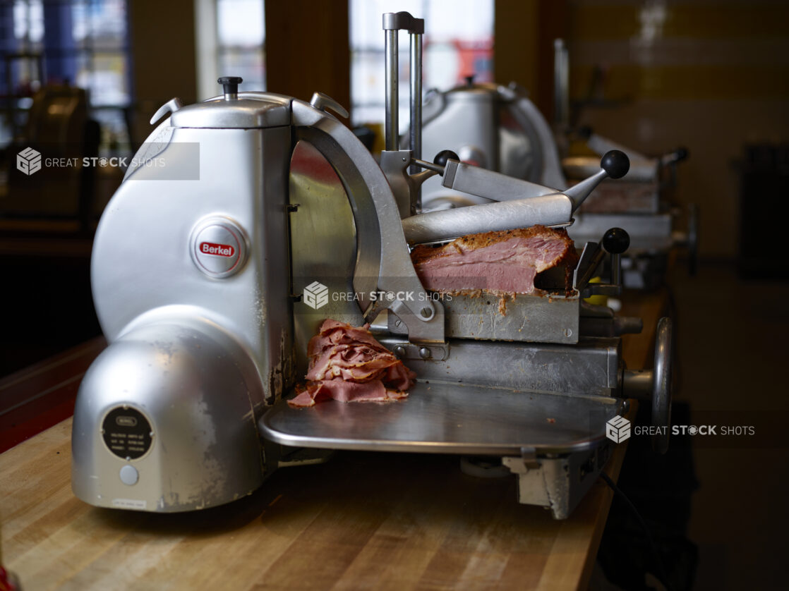 Commercial grade meat slicer, shaving pastrami in a restaurant