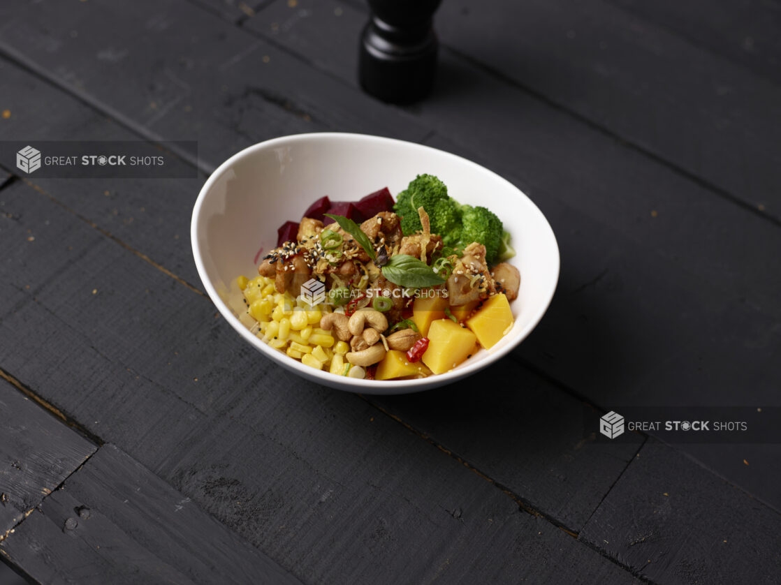 Asian cashew, chicken, mango bowl on a black wooden background