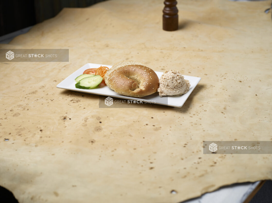 Sesame seed bagel with scoop of tuna salad on a white plate