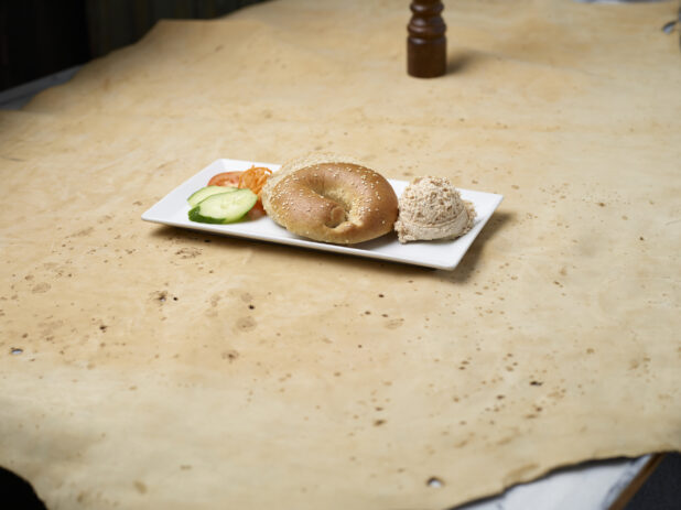 Sesame seed bagel with scoop of tuna salad on a white plate