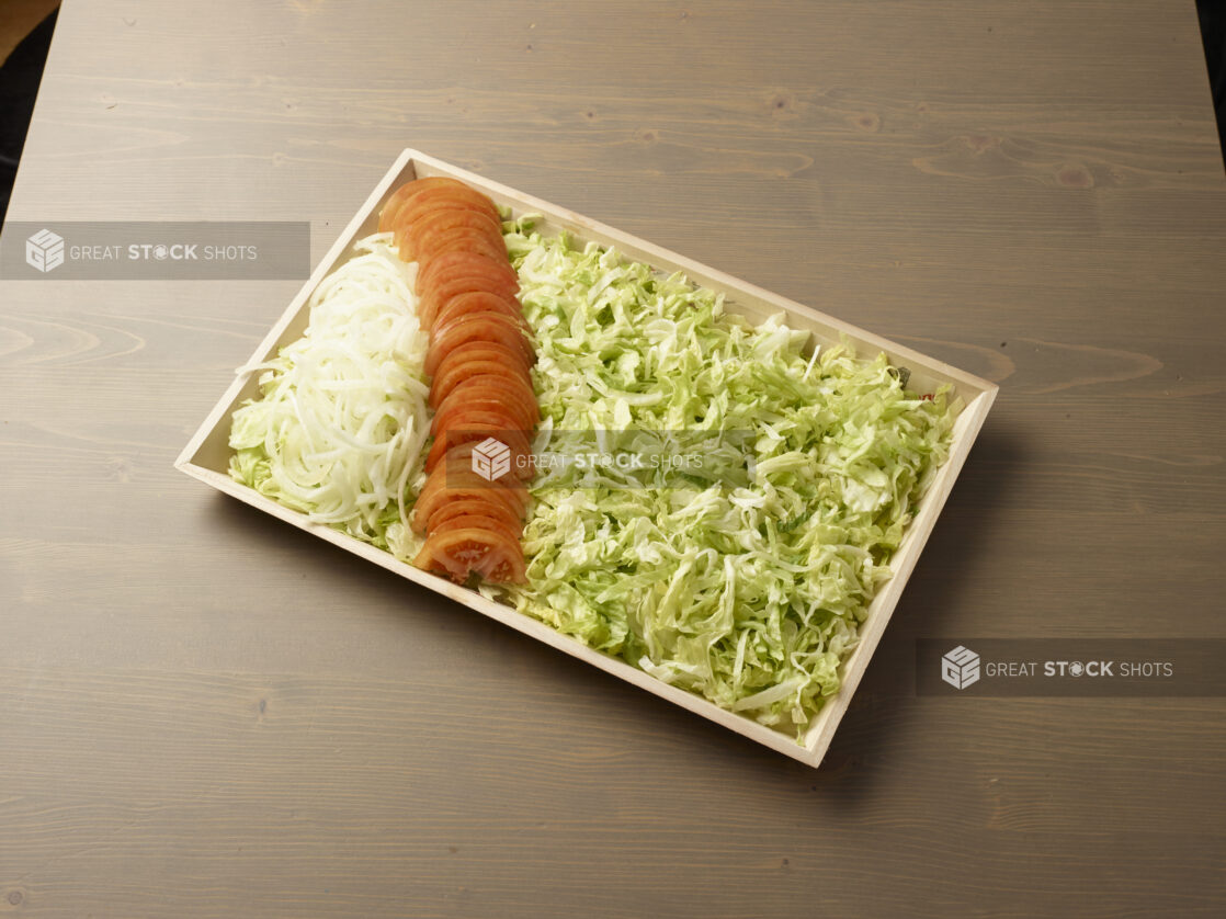 Wooden tray with toppings for kebab or shawarma platter components on a wooden background