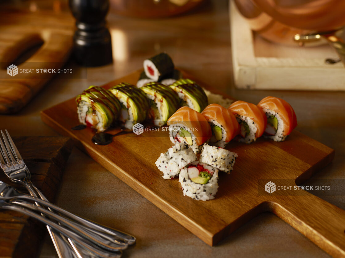 Various sushi rolls on a wooden cutting board