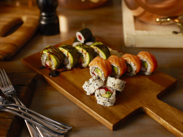 Various sushi rolls on a wooden cutting board
