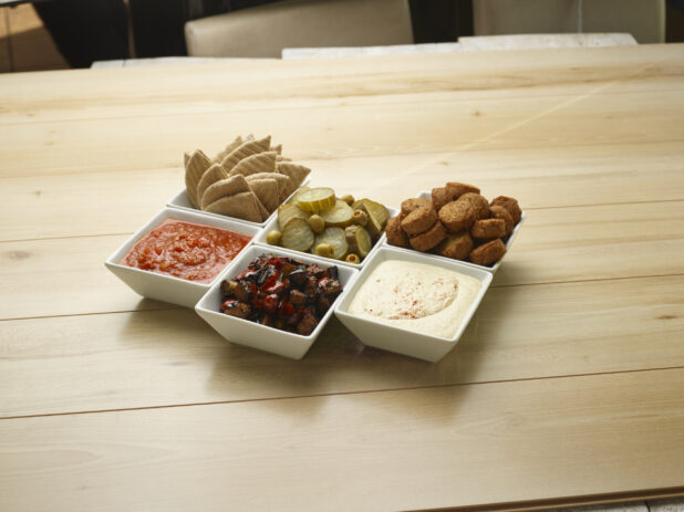 Various small white bowls of food and dips on a wooden background
