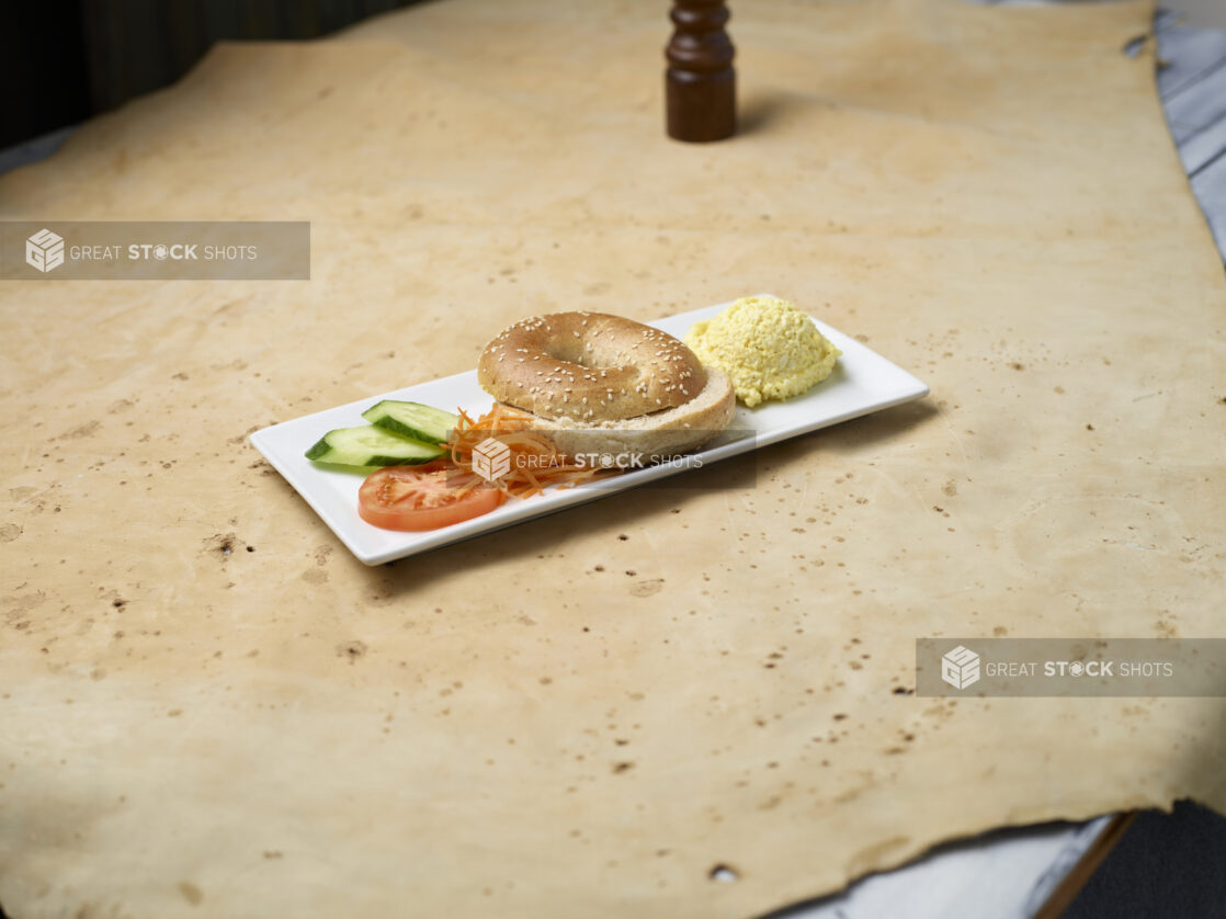 Sesame seed bagel with scoop of egg salad on a white plate