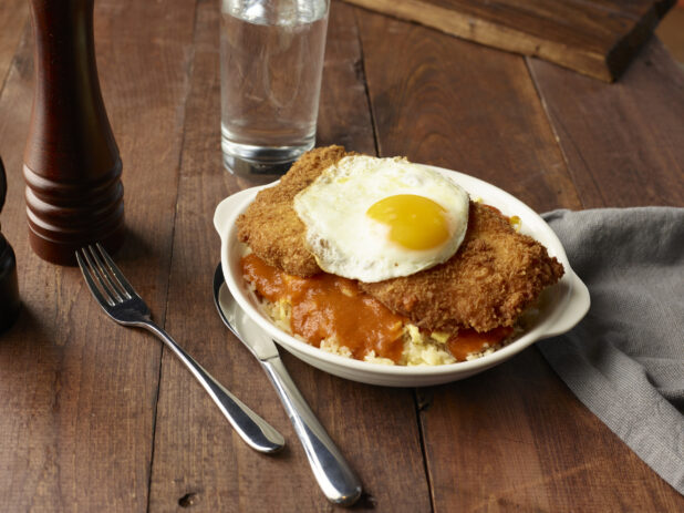 Fried chicken and egg dish on sauced rice in a skillet