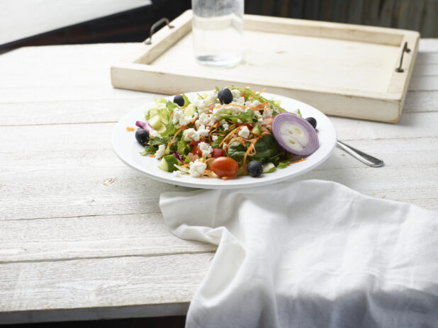 Bow of greek salad on a wooden background