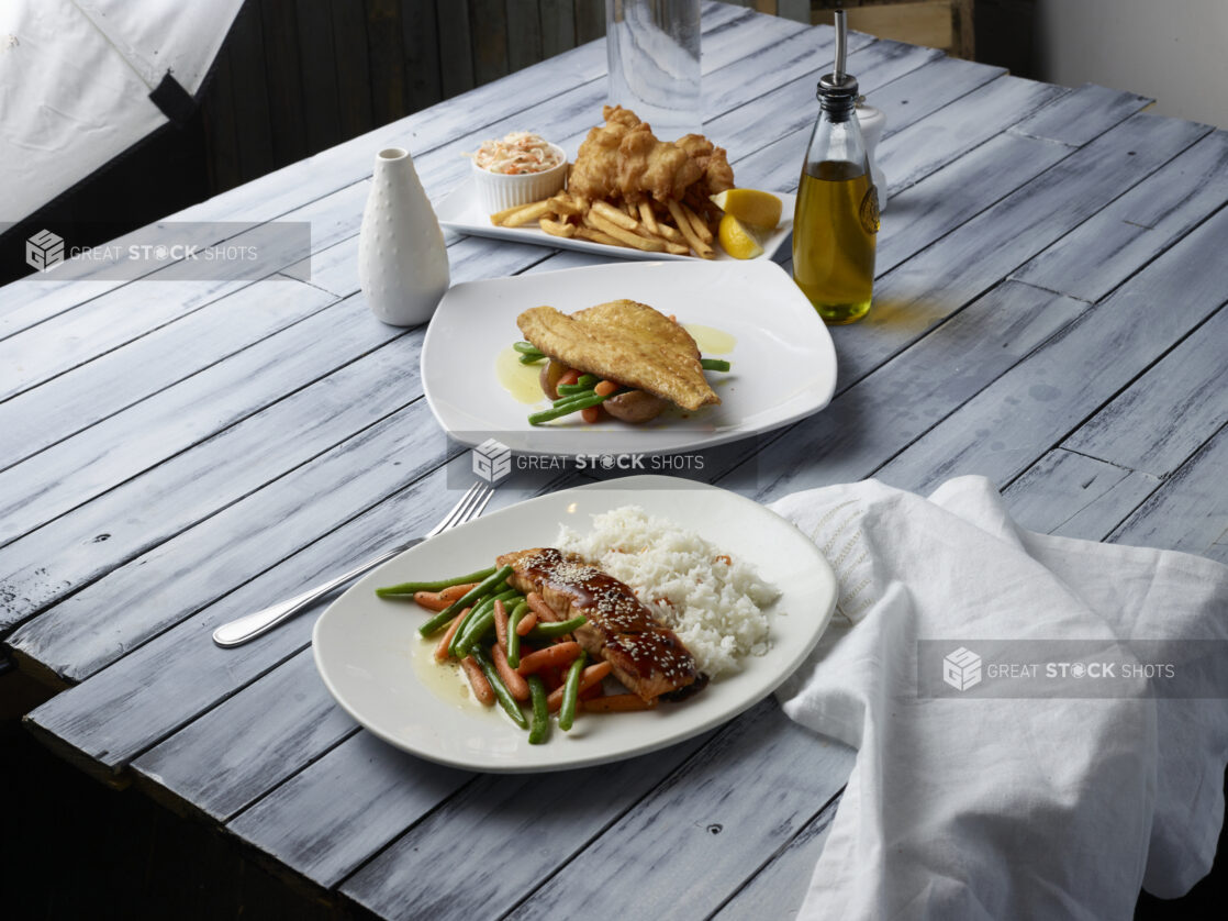 Various meals on white plates on a wooden background