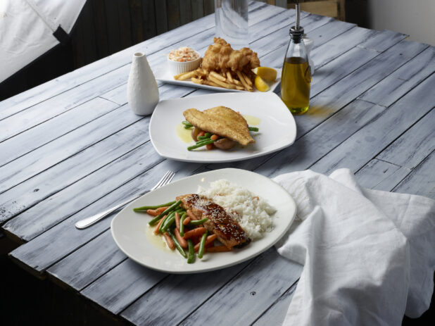 Various meals on white plates on a wooden background