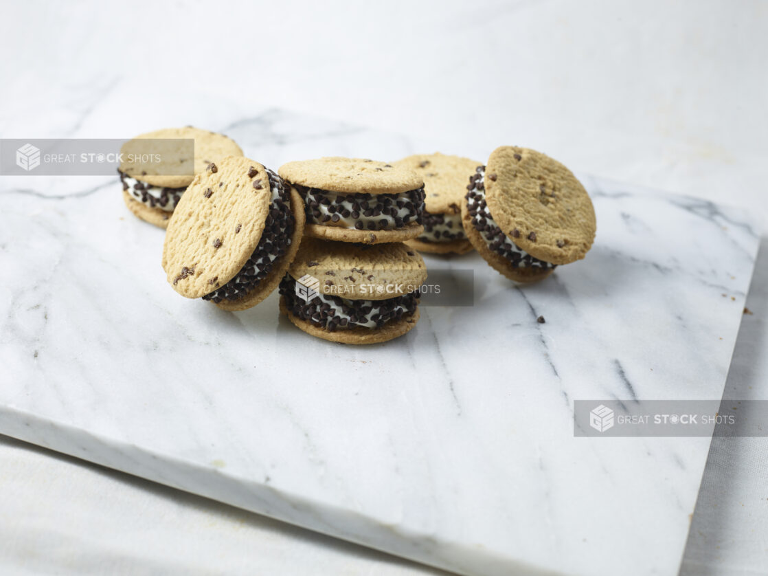 Many chocolate chip ice cream sandwiches stacked on a white marble slab