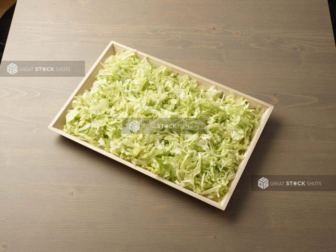 Wood catering tray filled with shredded lettuce, Middle Eastern platter, wood grain background