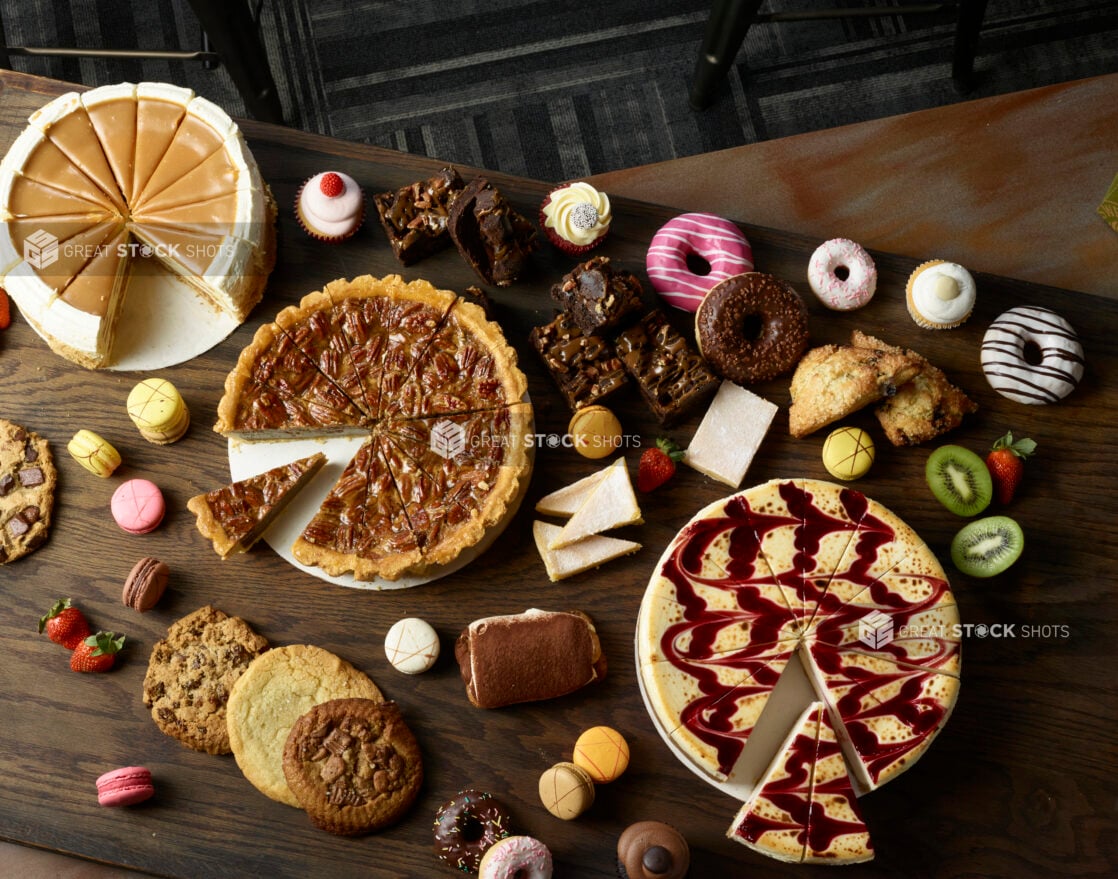 Overhead of cakes and other desserts on a dark wooden background, overhead