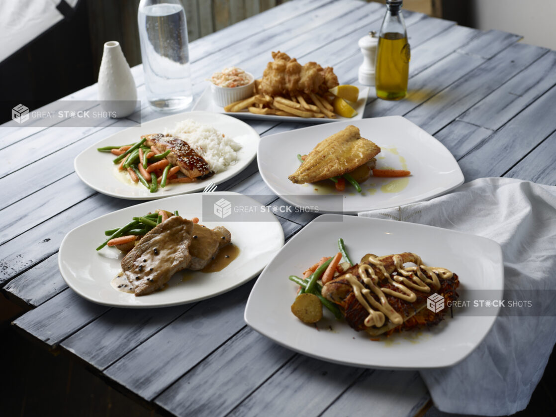 Various meals on white plates on a wooden background