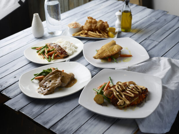 Various meals on white plates on a wooden background
