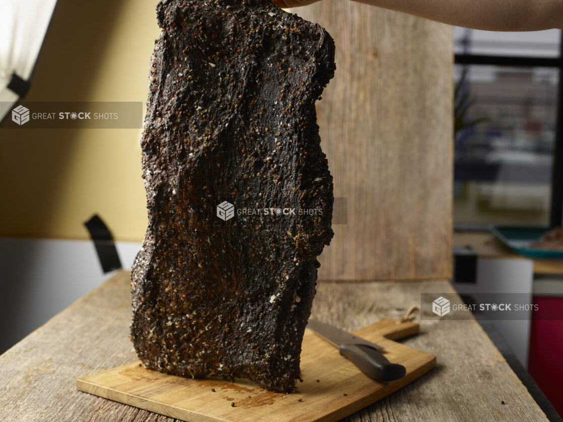 Large cut of seasoned brisket on a cutting board in a restaurant