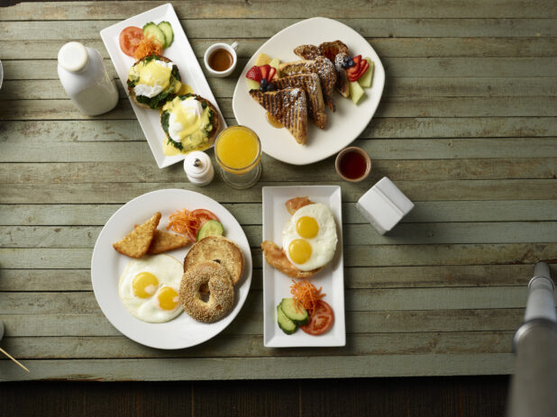Overhead view of different breakfast, brunch plates on wooden background