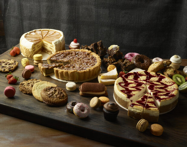 Various desserts / cakes on a wooden board on a dark wooden background