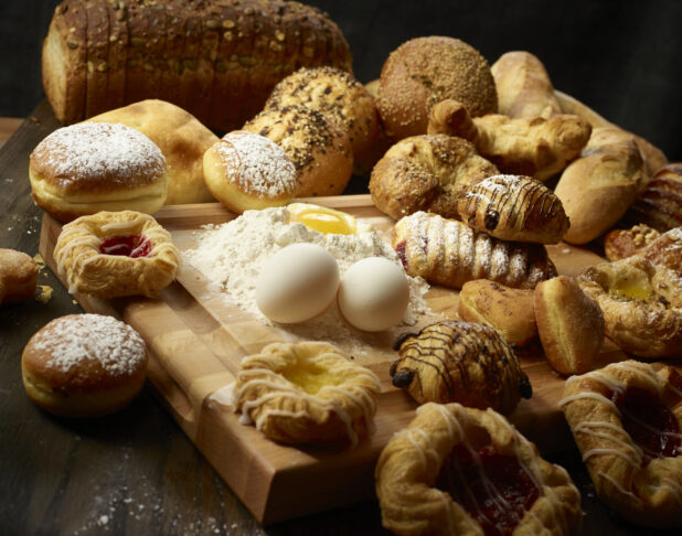 Collection of various desserts / pastries with fresh eggs and flour with an egg well on a wooden block
