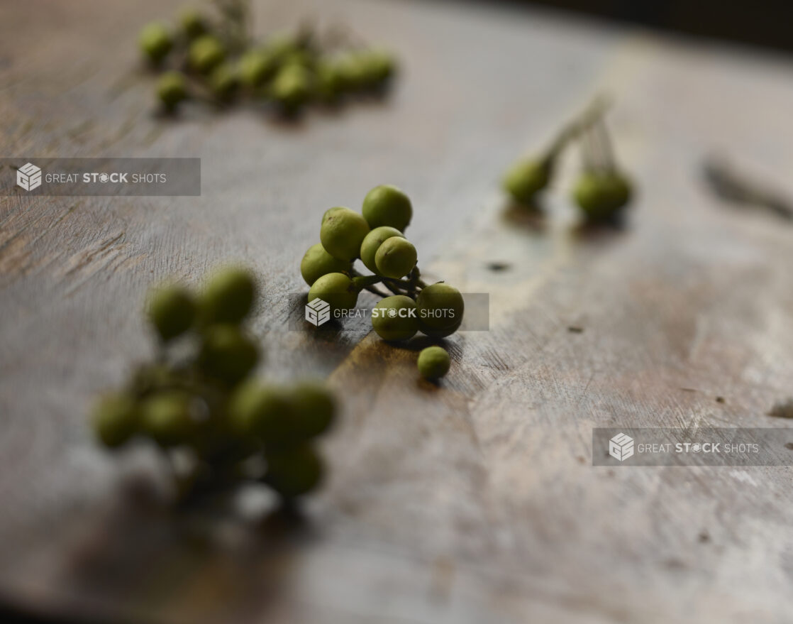 Clusters of fresh olives on the stem with a bokeh wooden background