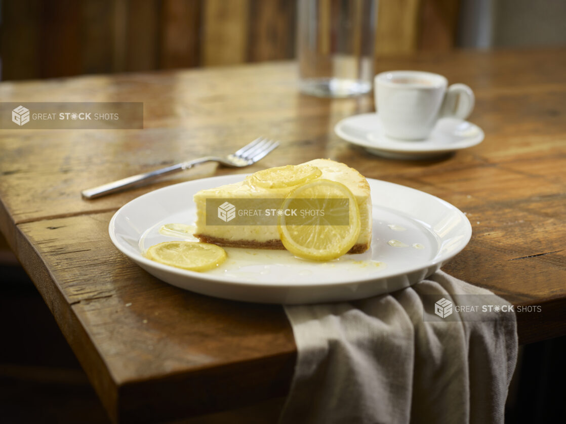 Slice of lemon cheesecake on a wooden table with coffee