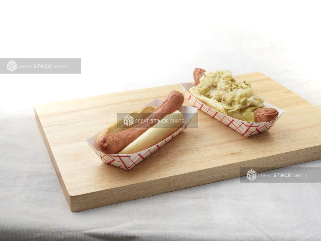 Two hot dogs on a wooden cutting board