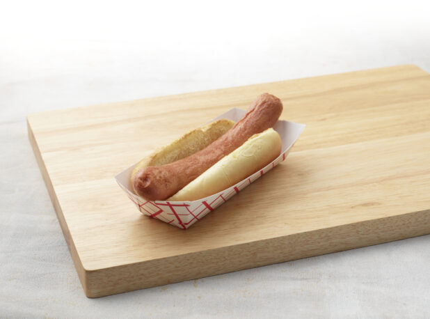 Plain hot dog with bun on a wooden cutting board